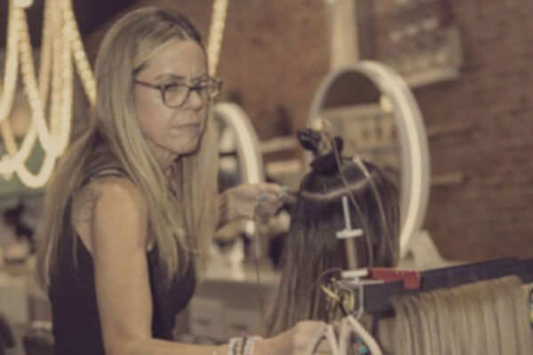 master stylist is focused on adding extensions to client's hair Hair Butler™ hair extension workstation tool