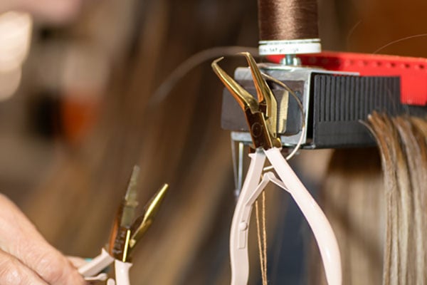 special pliers on magnetic side of Hair Butler™ hair extension workstation tool in salon