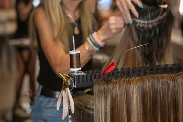 close up of pliers on magnetic side of Hair Butler™ hair extension workstation tool with extensions ready to be added