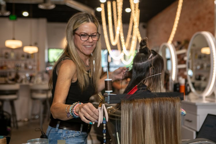 stylist uses Hair Butler™ hair extension workstation tool for a client