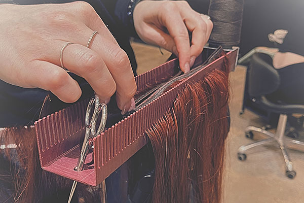 stylist gets red hair extensions ready in Hair Butler™ hair extension workstation tool