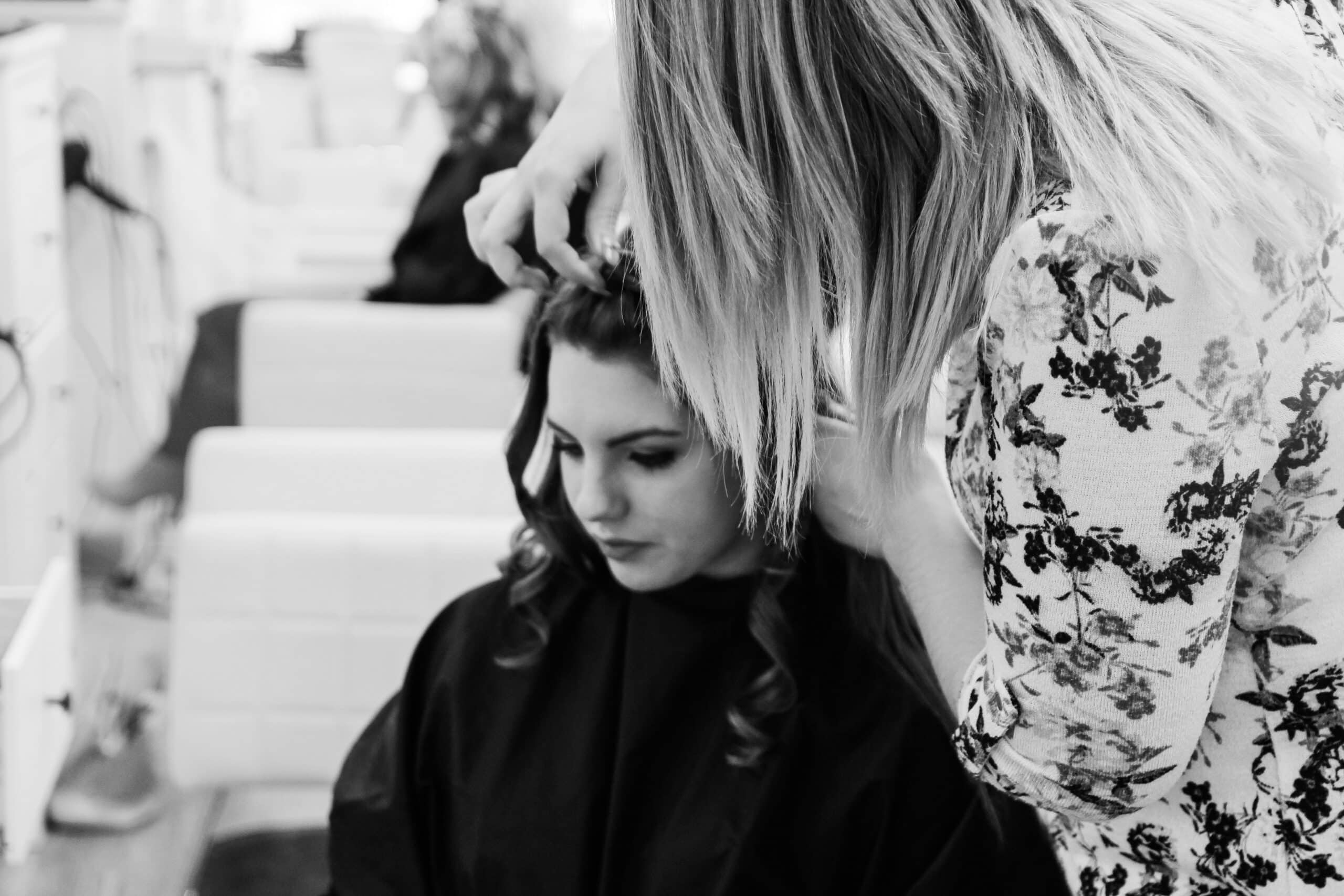 Hair extension stylist working behind the chair during a busy salon appointment