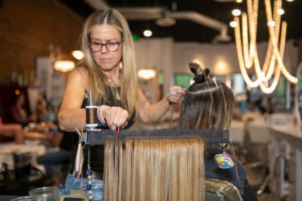 stylist stays organized by using Hair Butler™ hair extension workstation tool on client at salon
